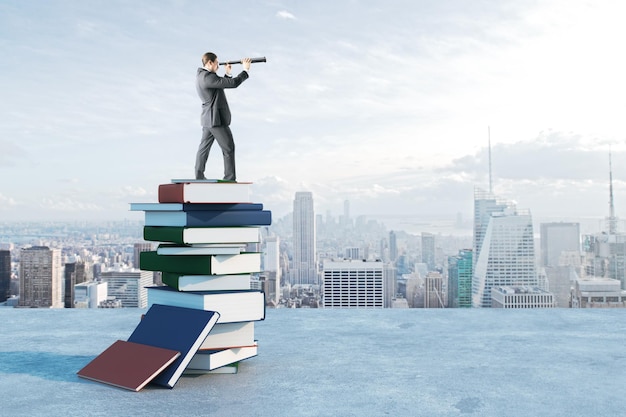 Businessman with binoculars standing on book