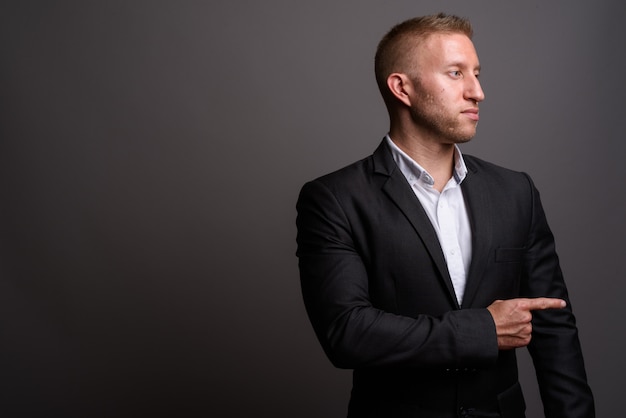 Businessman with blond hair on gray wall