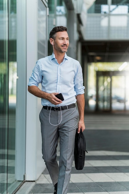 Businessman with cell phone and earphones on the go