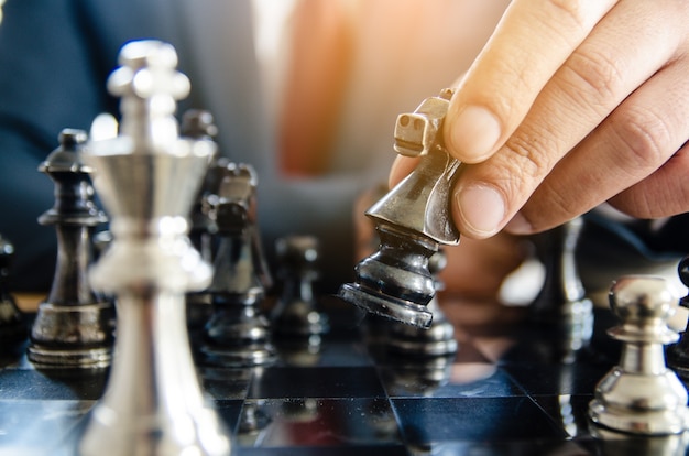 businessman with clasped hands planning strategy with chess figures