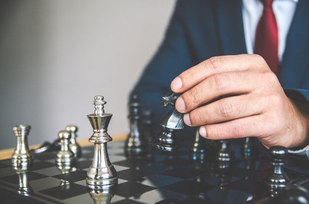  businessman with clasped hands planning strategy with chess 