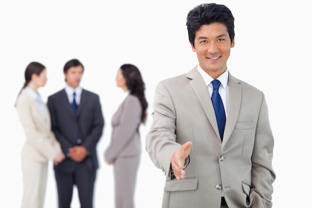 Businessman with colleagues behind him offering his hand