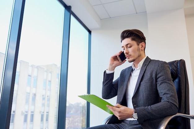 Businessman with documents hands of talking on a cell in modern 