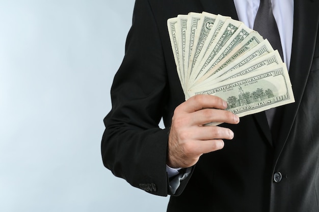 Businessman with dollar bills on light background closeup