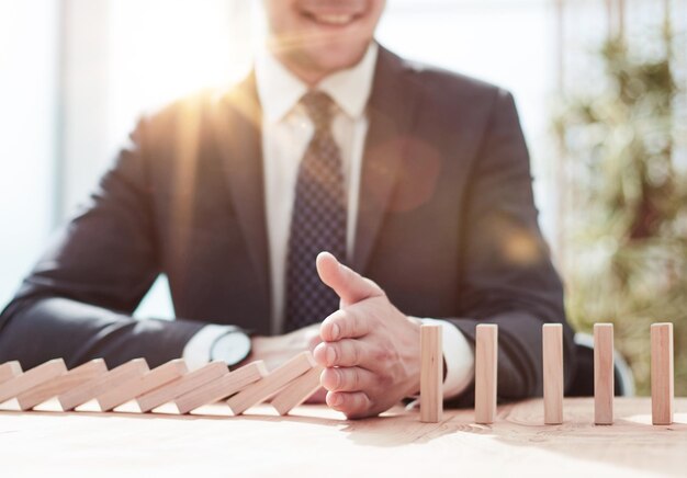 Photo businessman with dominoes in the office concept business risk