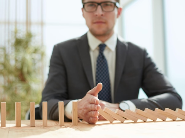 Businessman with dominoes in the office concept business risk