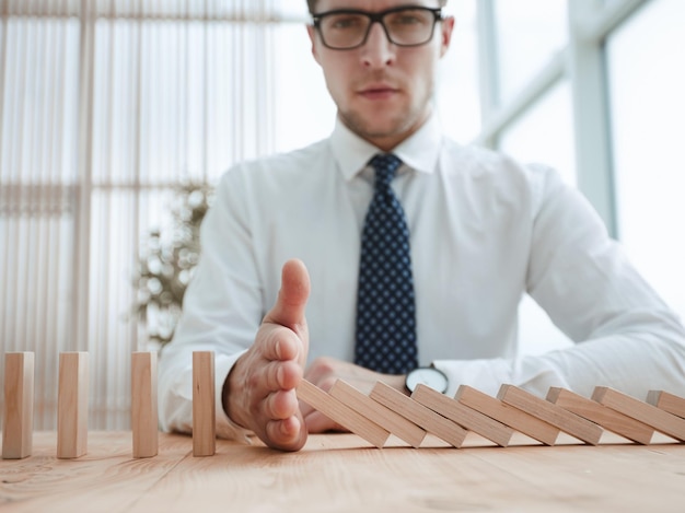 Businessman with dominoes in the office concept business risk