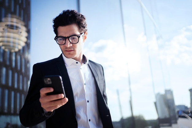 A businessman with glasses holds the phone goes to work in the office in a business