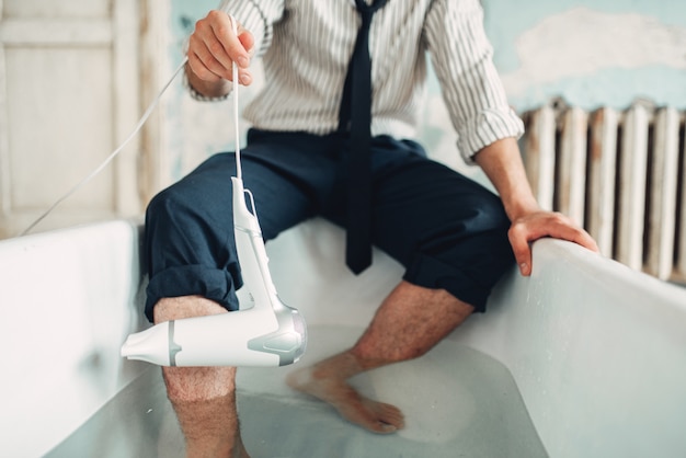 Photo businessman with hairdryer in bathtub, suicide man