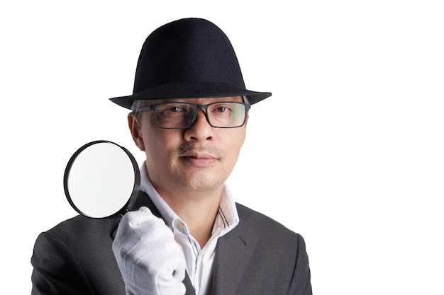 Businessman with hat holding magnifying glass against white background