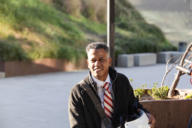 Businessman with helmet and electric scooter resting outdoors