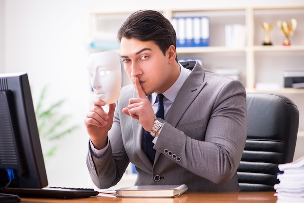 Businessman with mask in office hypocrisy concept