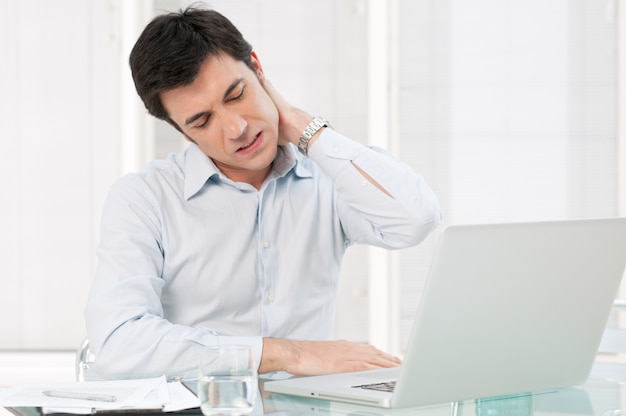 Businessman with neck pain after long hours at work