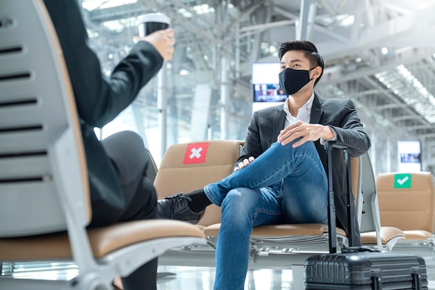 Businessman and woman with face mask protection casual meeting with social distancing seat at airport terminal new lifestyle business concept