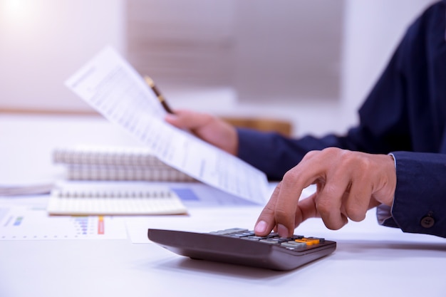 Photo businessman working on a desk with a calculator to calculate the numbers finance.