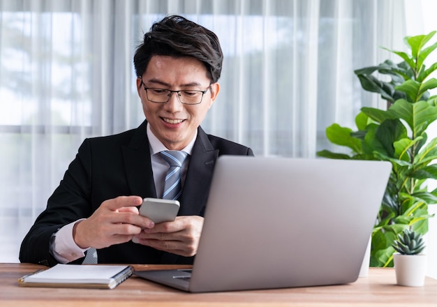 Businessman working on laptop at office desk and talking on the phone Jubilant