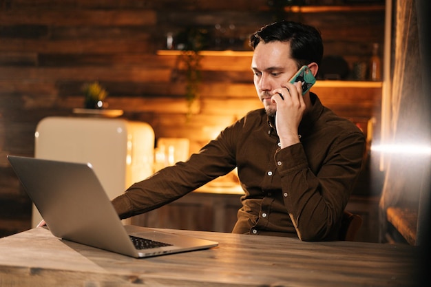 Businessman working on laptop and talking on mobile phone at the home. Concept of lifestyle in self-isolation in Coronavirus COVID-19 Pandemic.