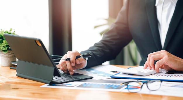 Businessman working at office with document on his desk, doing planning analyzing the financial report, business plan investment, finance analysis concept.Using calculator and tablet.