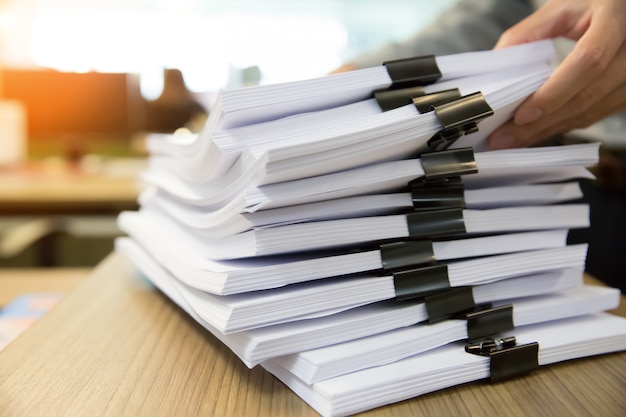 Businessman working in Stacks paper for searching information on work desk office.