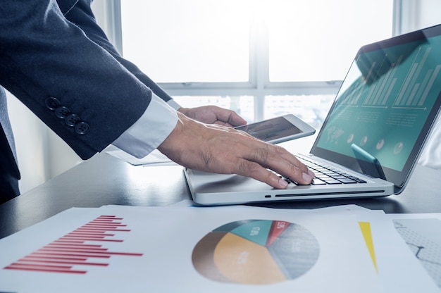 businessman working with digital tablet and laptop with financial document.