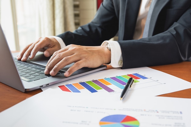 Businessman working with laptop with graph stock chart on table work from home concept.