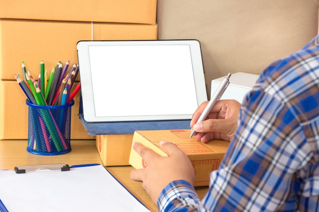 Businessman working with mobile phone and packing brown parcels box at home office