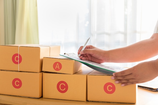 Businessman working with mobile phone and packing brown parcels box at home office