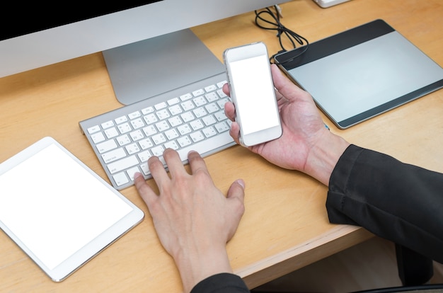 Businessman working at Workplace with computer, tablet, smart phone and keyboard on wooden table