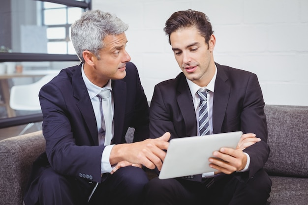 Businessmen discussing while holding digital tablet