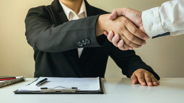 The businessmen finished the meeting and the happy businessman's handshake after the contract was made to be a teamwork partner together.