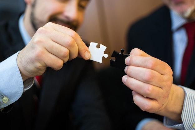 Businessmen joining puzzle pieces together