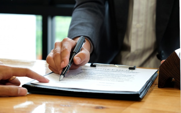 Businessmen selling the house pointing at the signing of the sales contract in the office.