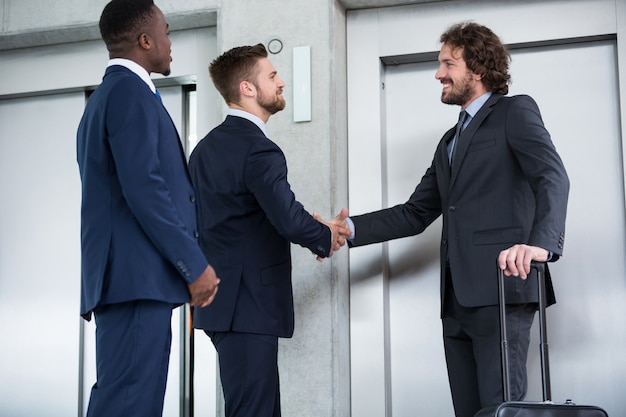 Businessmen shaking hands while waiting for elevator