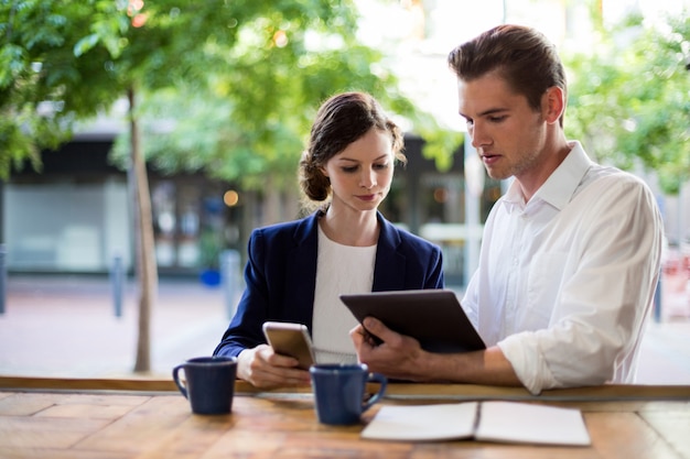 Businesspeople discussing over digital tablet at counter