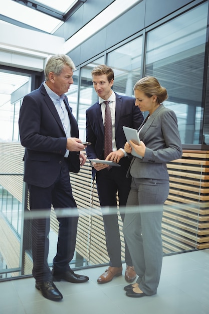 Businesspeople discussing over electronic devices in the passageway