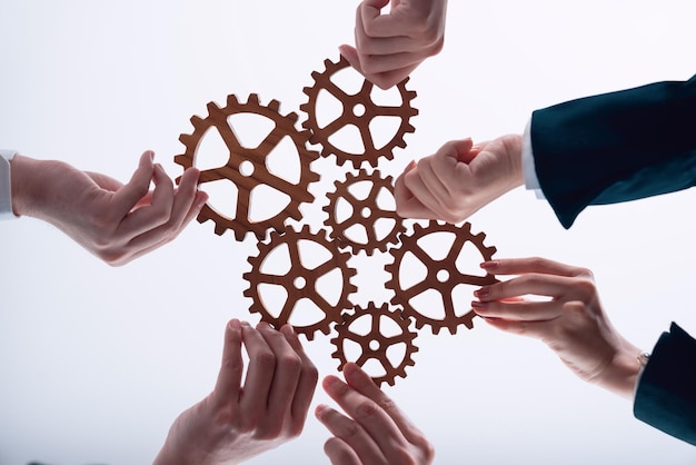 Businesspeople hand holding gears and join together from bottom view in harmony