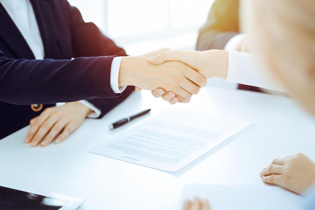 Businesspeople or lawyers shaking hands finishing up meeting or negotiation in sunny office Business handshake and partnership