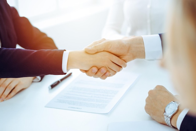 Businesspeople or lawyers shaking hands finishing up meeting or negotiation in sunny office. Business handshake and partnership.