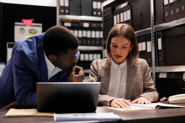 Businesspeople managing financial documentation, analyzing corporate administrative documents. Diverse managers discussing bookkeeping report in storage room, organizing business files