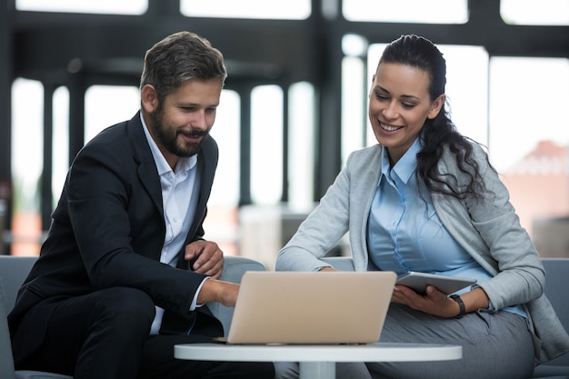 Businesspeople sitting and discussing over laptop