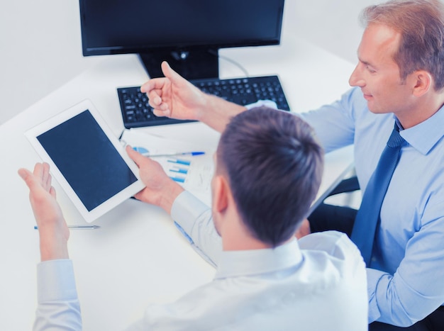 businesss and office concept - businessmen with notebook and tablet pc discussing graphs on meeting