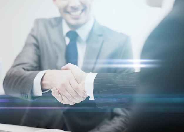 businesss and office concept - two businessmen shaking hands in office