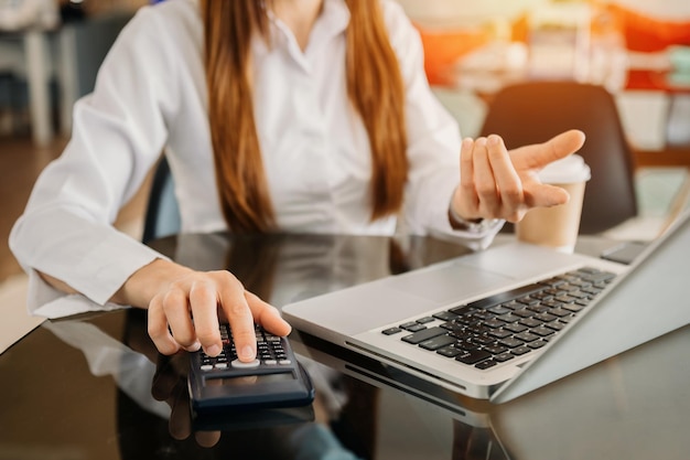 Businesswoman or accountant hand typing laptop working to calculate on desk about cost at home officexA