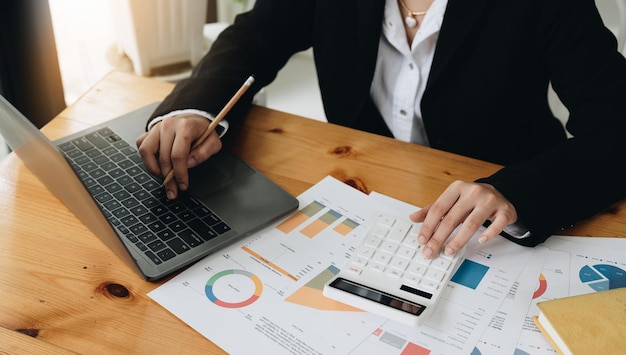 Businesswoman accountant working on desk office with using a calculator to calculate the numbers finance accounting conceptxA