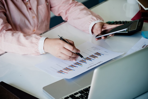 Businesswoman analyzing financial data on smartphone and computer screen.Close up