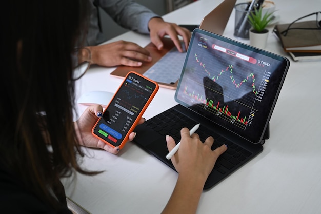 Businesswoman analyzing graph on computer tablet and using smart phone