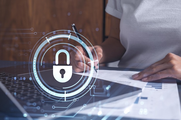 A businesswoman in casual wear signing the contract to prevent probability of risks in cyber security Padlock Hologram icons over the working desk