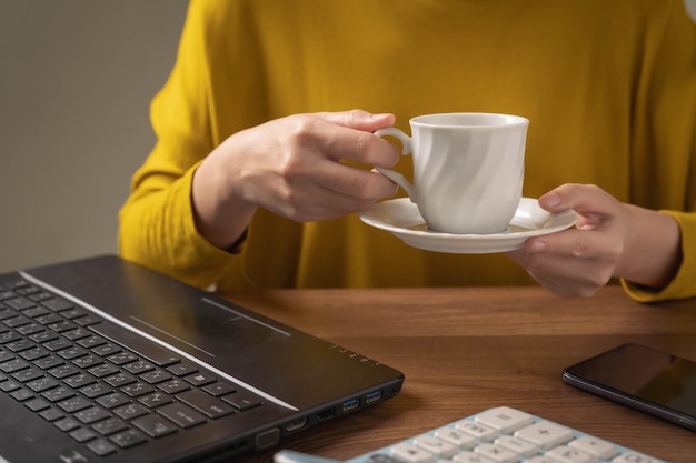 Businesswoman drinking coffee at work to keep her friend awake and feeling refreshed at work.