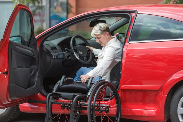 Businesswoman a driver with a disability getting into a red car transport driving and physical