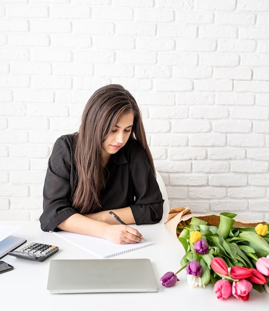 businesswoman florist writing in notebook or calendar at the office